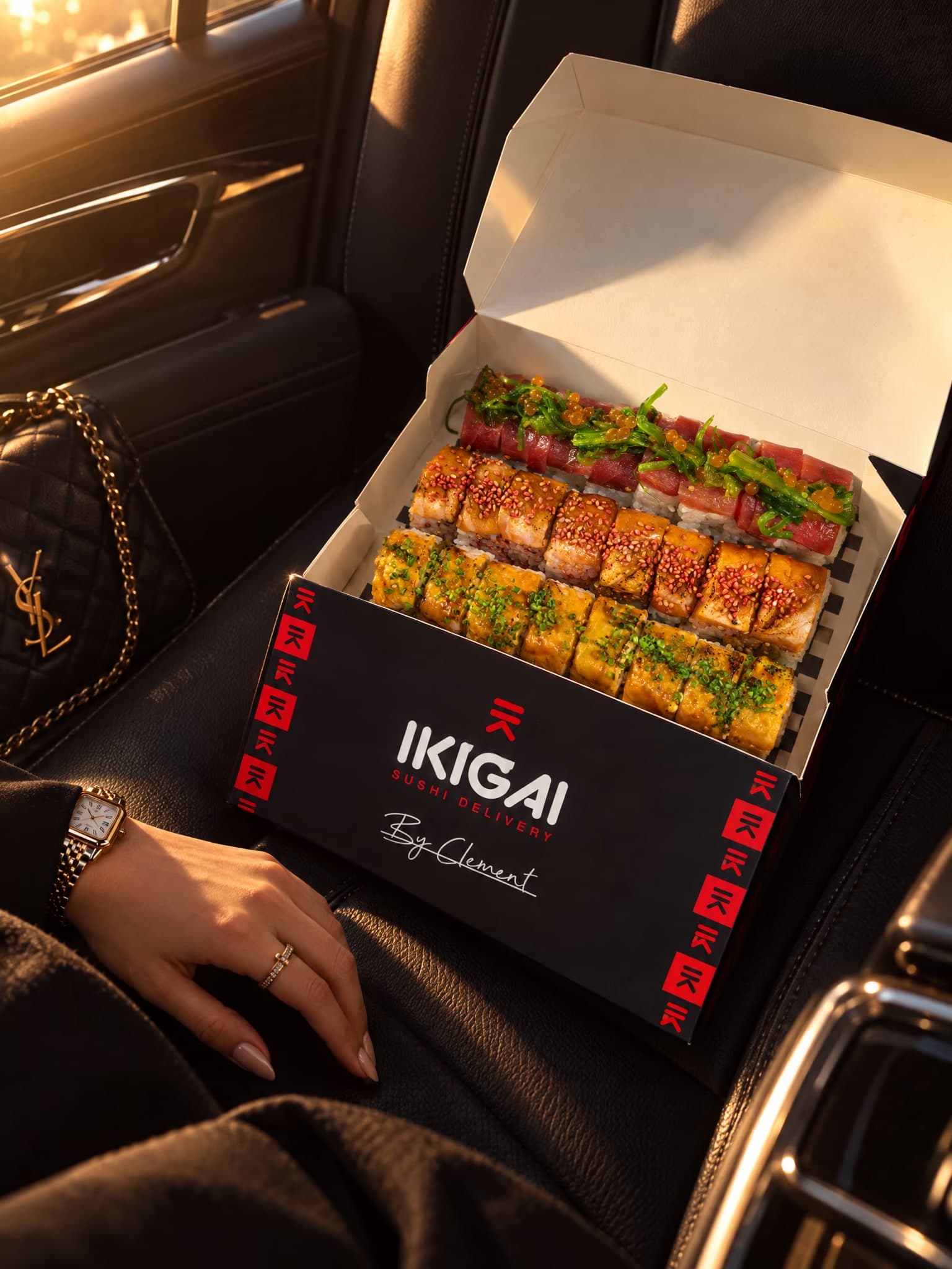 Caja de Ikigai abierta con tres filas de rolls, sobre el asiento de un coche